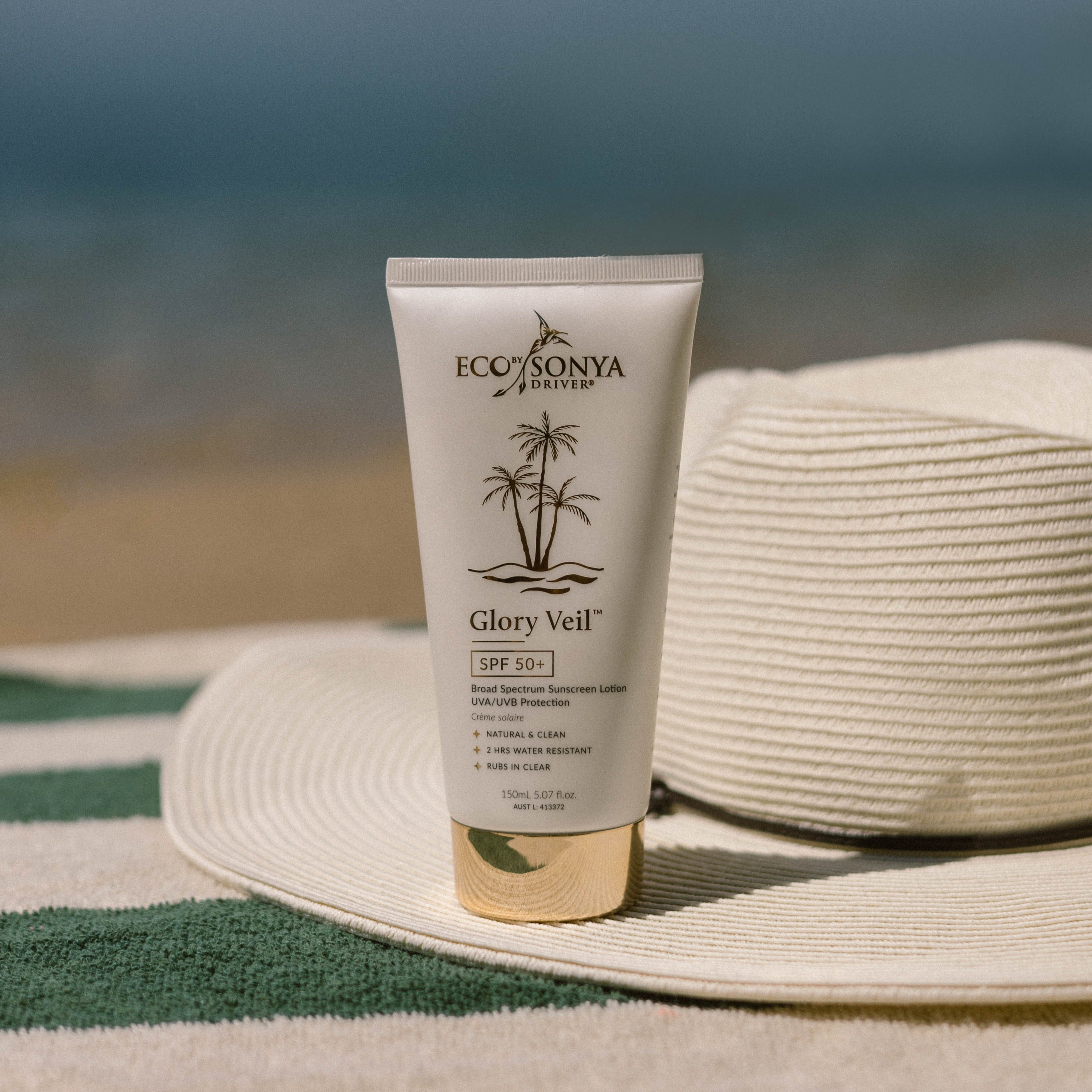 Glory Veil SPF 50+ Eco By Sonya  natural sunscreen on the beach with hat and towel