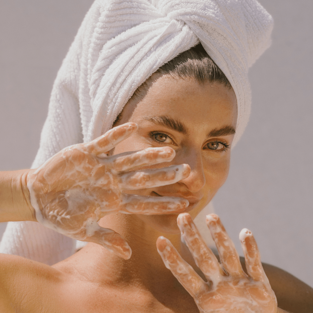 Woman with towel in hair using Super Citrus Cleanser, foamy hands