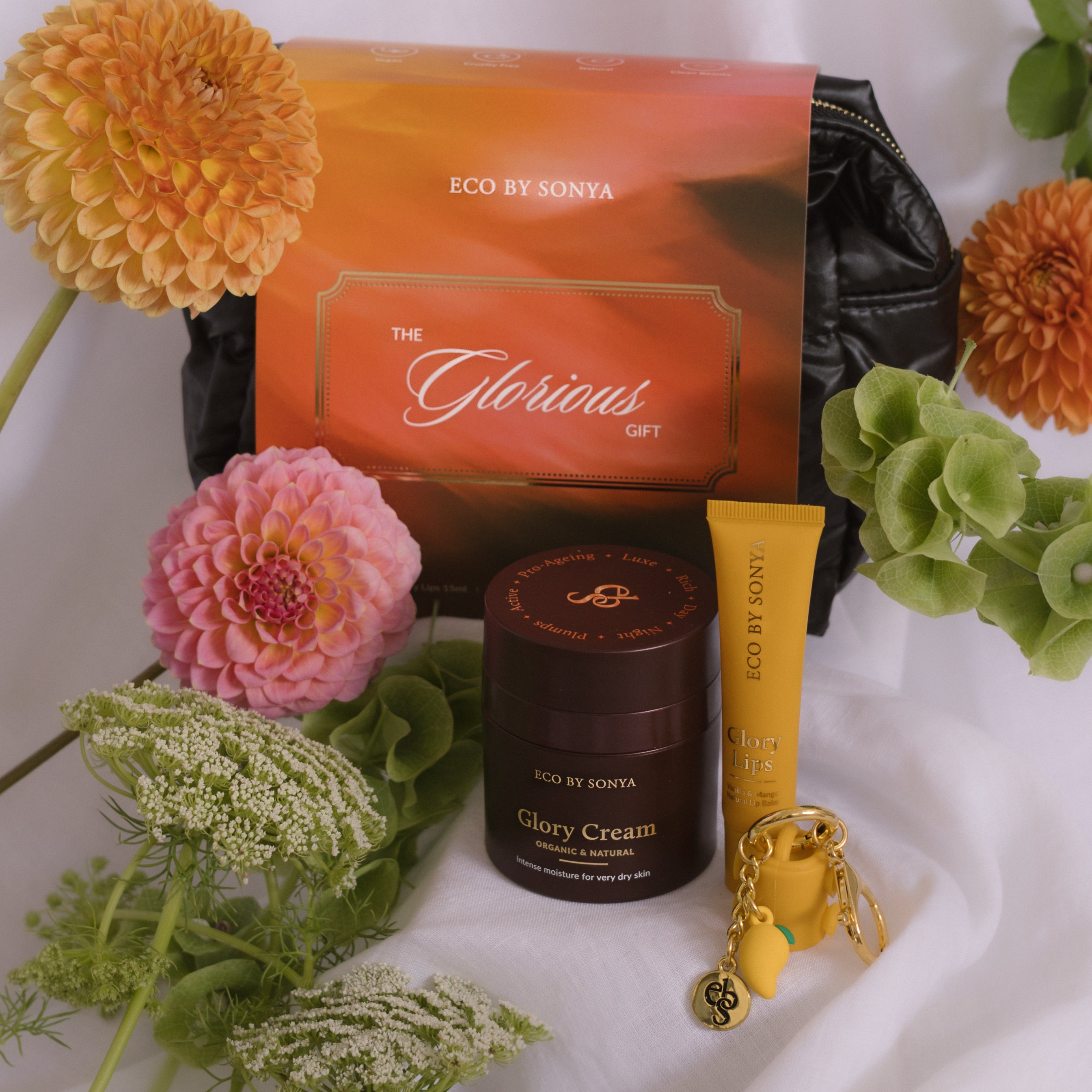 Cosmetic set Glorious Gift with 'Eco by Sonya' products including a makeup bag, Glory Cream, and Glory Lips, surrounded by flowers.